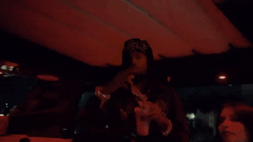a man in a bandana is holding a cup and giving a thumbs up while standing on a boat .