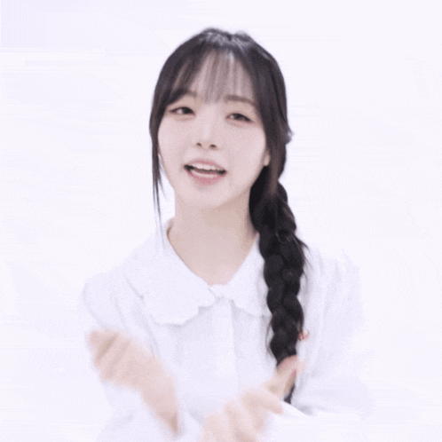 a woman in a white shirt with braided hair is making a peace sign