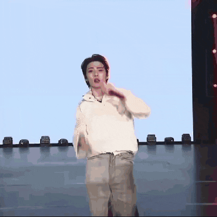 a man in a white shirt is singing into a microphone on stage