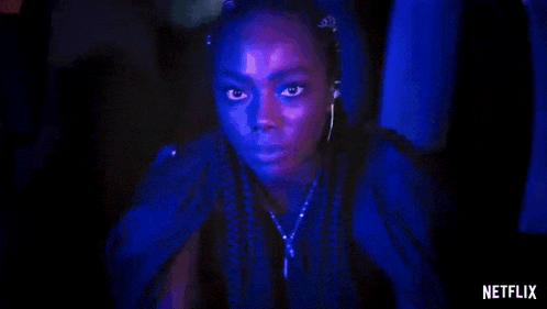 a woman with braids and earrings is looking at the camera .