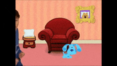 a blue dog standing next to a red chair in a room
