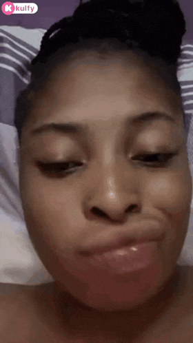 a woman is making a funny face with her mouth open while laying in bed .