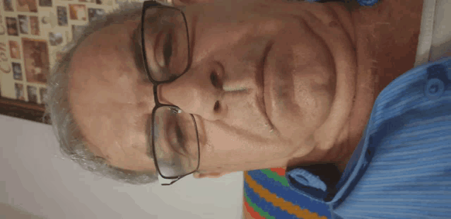 a man wearing glasses and a blue shirt is looking down at something