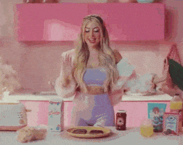 a woman is singing into a microphone while cooking in a pink kitchen .