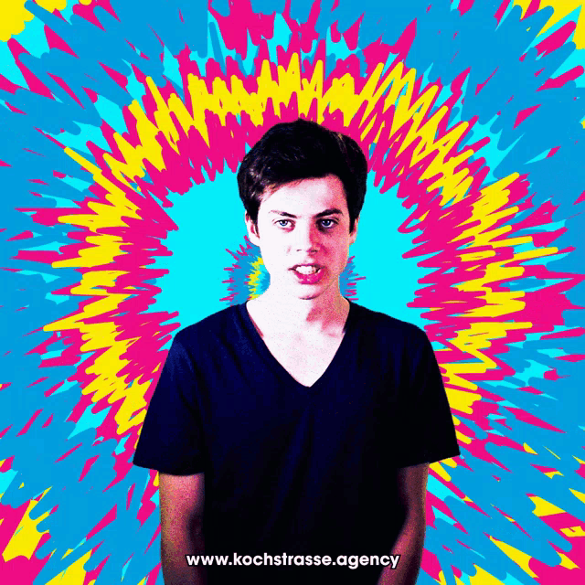 a young man stands in front of a colorful background with the website www.kochstrasse.agency written below him