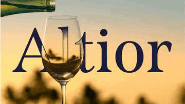 a glass of wine is being poured from a bottle with the word altior written above it