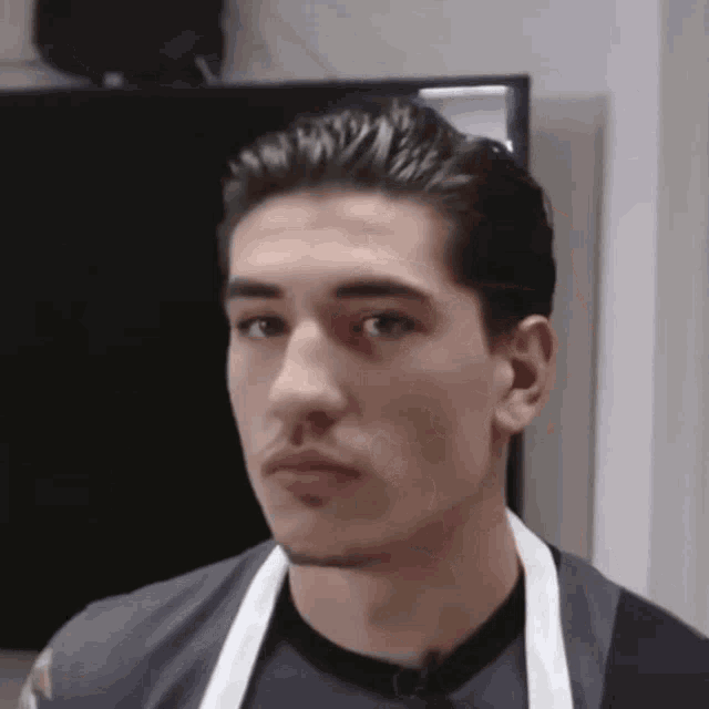 a man wearing a black shirt and an apron looks at the camera