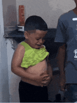 a young boy without a shirt is crying while holding his belly ..
