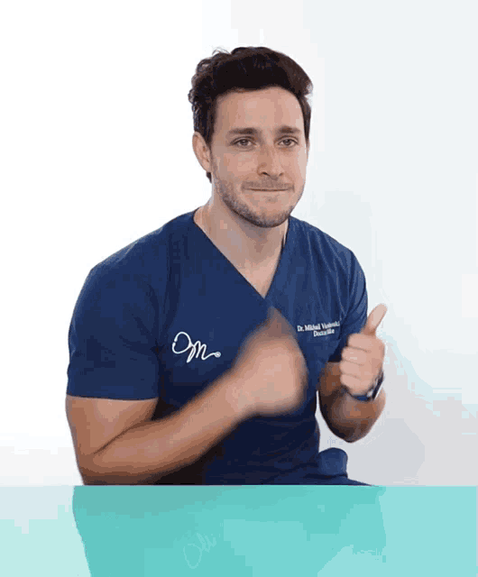 a man wearing a blue scrub top that says om