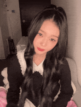 a girl with long black hair is wearing a black top with white lace trim