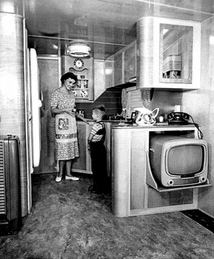 a black and white photo of a kitchen with a woman and child