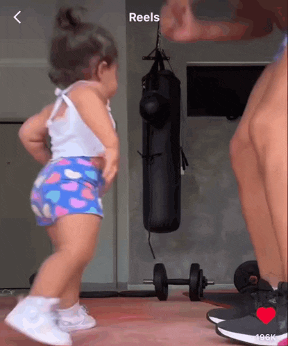 a little girl is dancing in front of a punching bag that says reels on the bottom