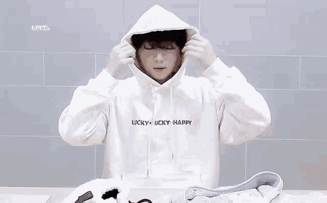 a man wearing a white hoodie is tying a string around his hood .