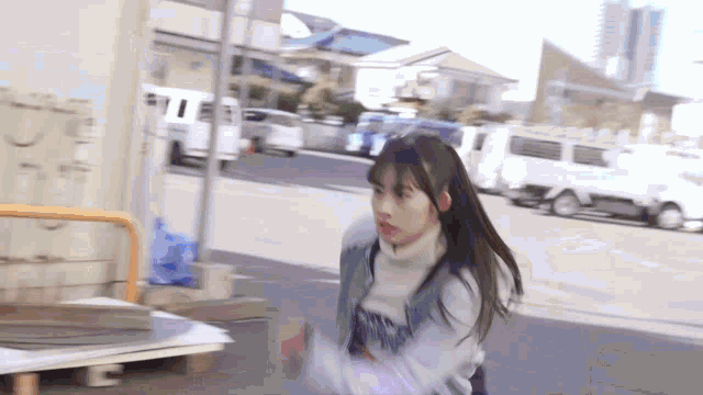 a girl with long hair is running down a street with a truck in the background