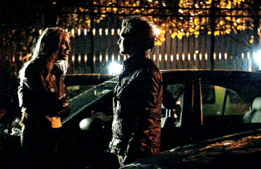 a man and a woman are standing next to each other in front of a car