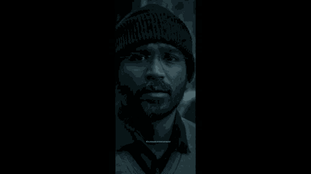 a man in a plaid shirt is smiling in the dark .