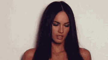 a woman with long dark hair is making a funny face .