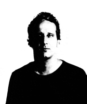 a man is wearing a black shirt and looking at the camera .