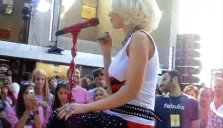 a woman is singing into a microphone in front of a crowd while wearing a fabulis shirt .