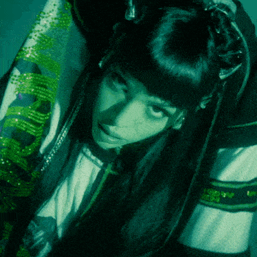 a woman with long black hair is wearing a green shirt that says ' abercrombie & fitch ' on the sleeves