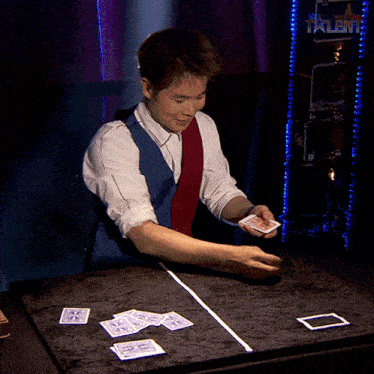 a man in a blue vest and red tie is playing cards on a table in front of a wall that says talent
