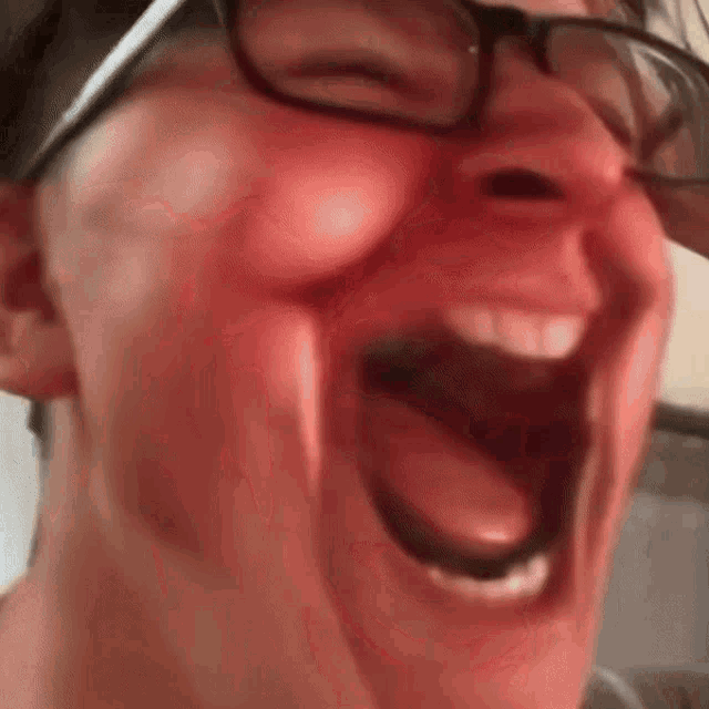 a man wearing glasses is making a funny face with his mouth wide open .