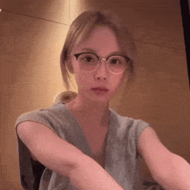 a woman wearing glasses is taking a selfie .