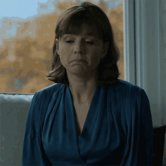 a woman in a blue shirt looks out a window