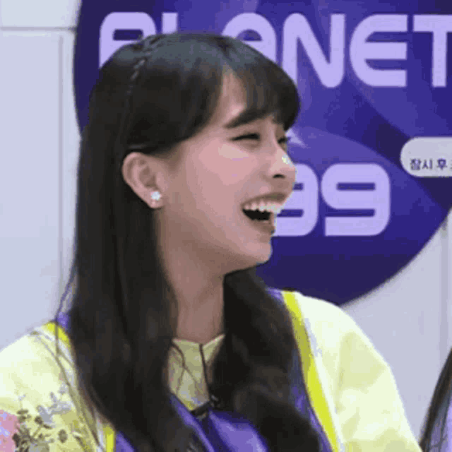 a girl laughs in front of a sign that says planet 99