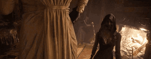 a woman in a very large dress is standing next to a woman in a hood .