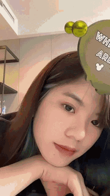 a close up of a woman 's face with a green balloon that says " what are you "