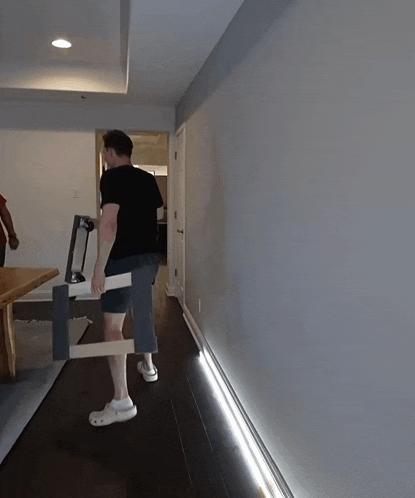 a man wearing a jacks jones shirt is carrying a piece of furniture