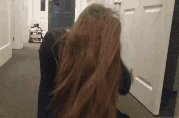 a woman with red hair is standing in front of a white door