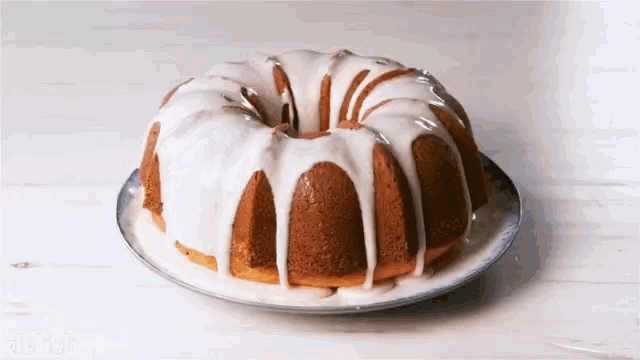 a bundt cake with white frosting on a white plate