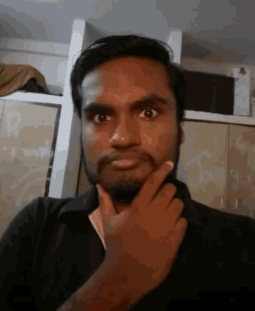 a man with a beard is making a funny face with his hand on his chin