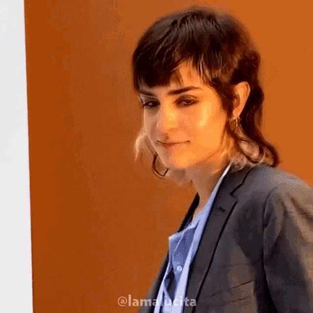 a woman with short hair is wearing a suit and blue shirt .