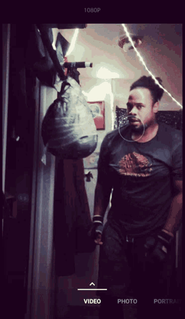 a man in a black shirt is standing in front of a wall with a bag hanging on it