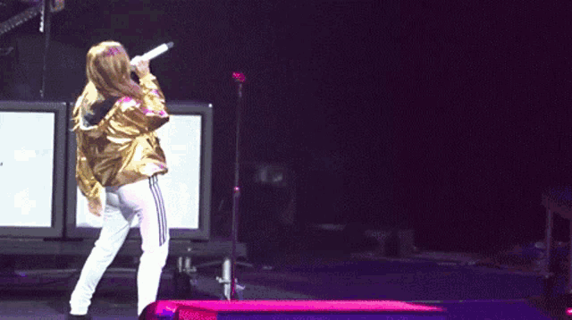 a woman is singing into a microphone on a stage