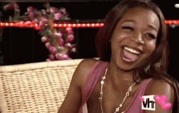 a woman is sitting on a wicker couch laughing with her tongue hanging out .
