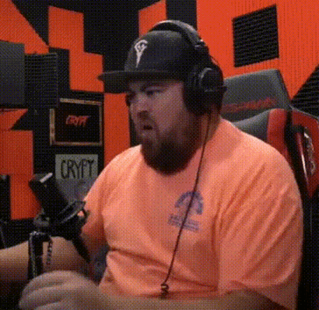 a man wearing headphones and an orange shirt is sitting in a chair .