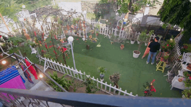 an aerial view of a garden with a white picket fence and lots of potted plants