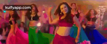 a group of women are dancing in a room with a sign that says kulfyapp.com on it .