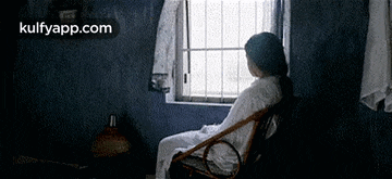 a woman is sitting in a chair in front of a window .