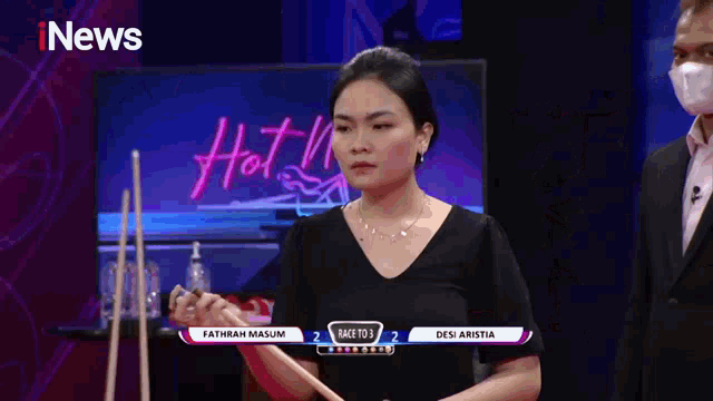 a woman holding a pool cue in front of a tv screen that says hot news