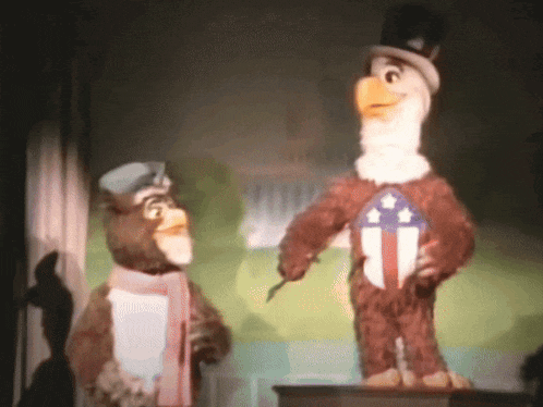 two stuffed animals standing next to each other one of which is a bald eagle