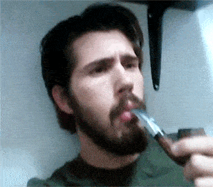 a man with a beard smoking a pipe with a lighter in his mouth