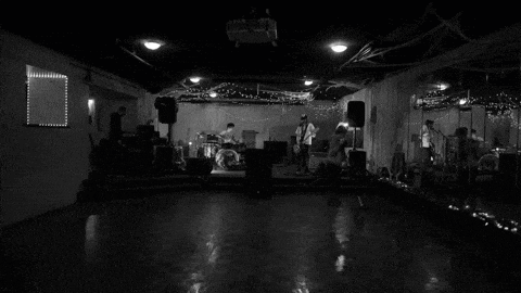 a black and white photo of a band playing instruments in a dark room