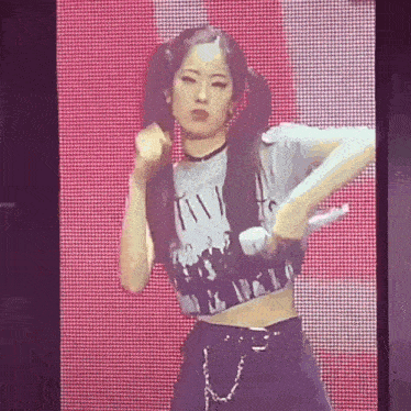 a woman in a crop top and pigtails is dancing on stage .