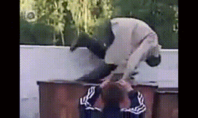 a man is doing a trick on another man 's head while standing on a table .