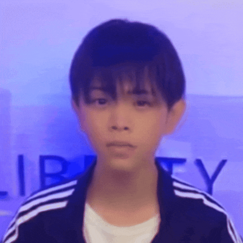 a young boy wearing a black and white adidas jacket is looking at the camera .